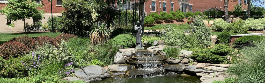 st martin de porres statue at the koi pond in summer